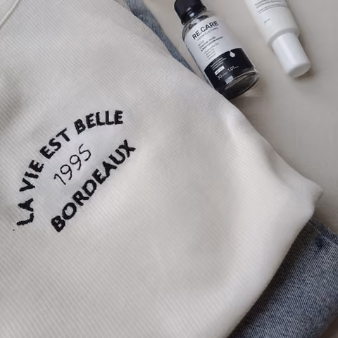 Skincare bottles resting on a knitted sweater